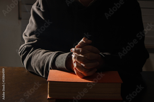 Slika na platnu Religion concept, Young asian man reads bible and hands folded to prayer for fai