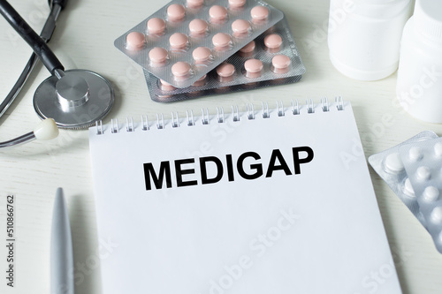 Text MEDIGAP on a table with stethoscope,pills and pen, medical concept. photo