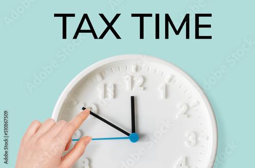 A woman's hand moves the arrow on the clock, close-up. Tax time. The concept of paying taxes and deadlines