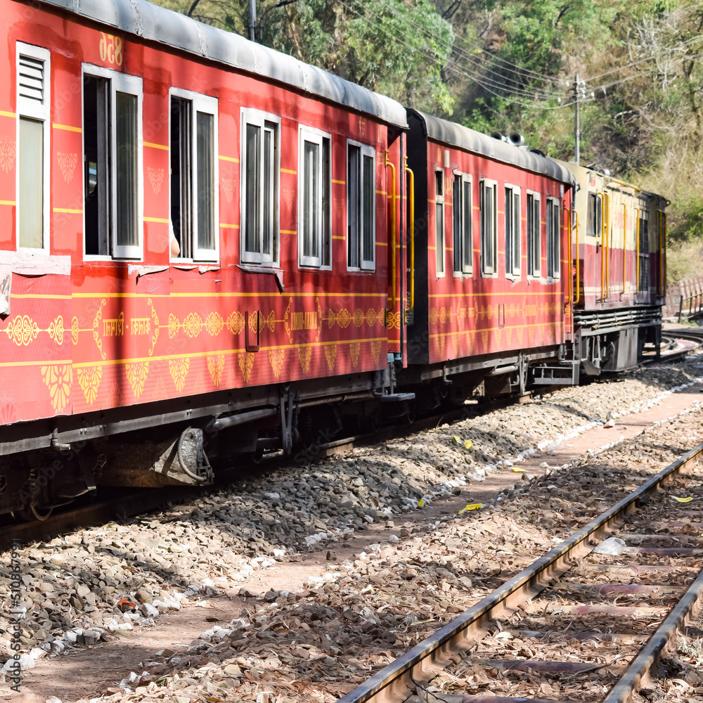 Toy Train moving on mountain slopes, beautiful view, one side mountain, one side valley moving on railway to the hill, among green natural forest. Toy train from Kalka to Shimla in India