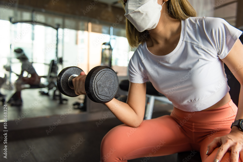 exercising with a dumbbell in the gym is a young, attractive woman. exercising with a dumbbell in the gym is a young, attractive woman.