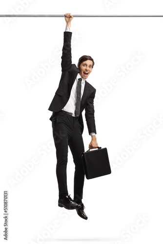 Businessman hanging and holding onto a bar photo
