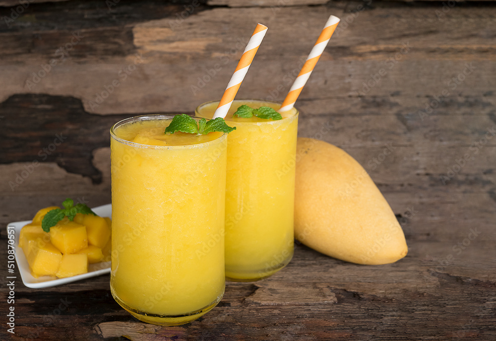 Fototapeta premium Mango juice fruit smoothies yogurt drink yellow healthy delicious taste in a glass slush for weight loss on wooden background.