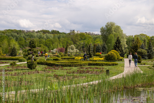 Park alley in Dendrariu, Chisinau. People walking on alley, spring park.
