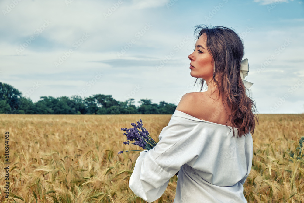 Portrait of a young girl in a field with wheat
