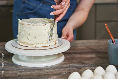 female hands smear the cake with cream using a special spatula