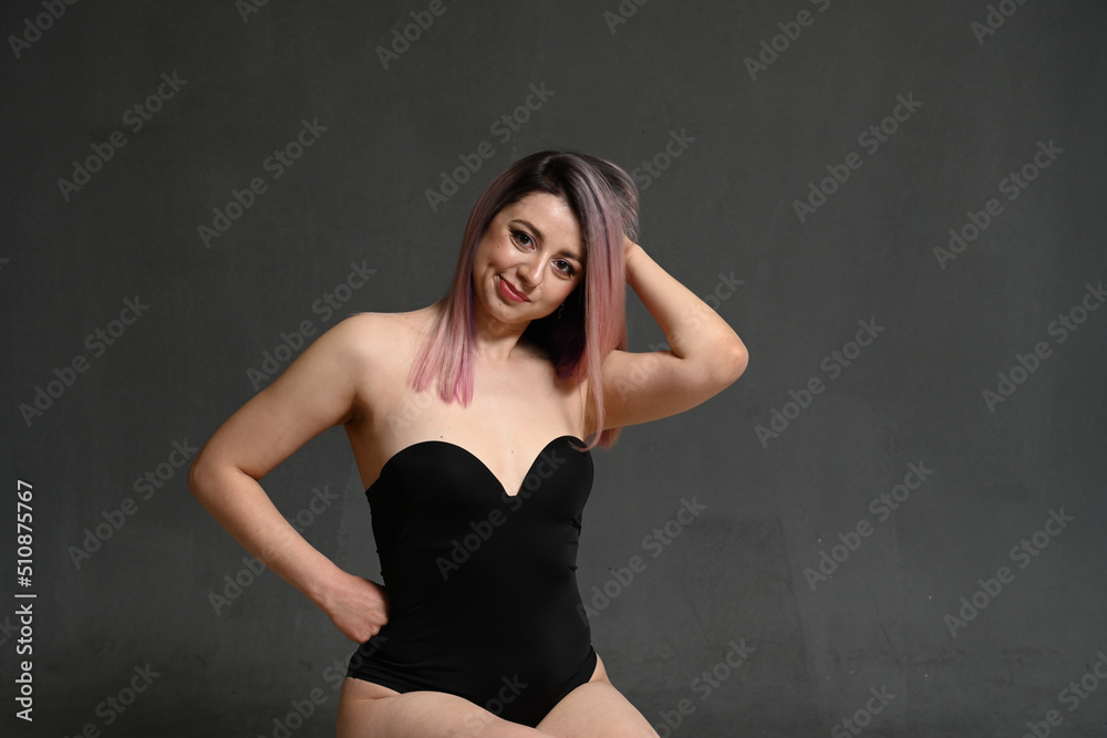 Front view model with dyed hair smiling holding her head on gray background Front view model with dyed hair smiling holding her head on gray background