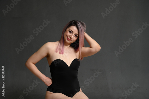 Front view model with dyed hair smiling holding her head on gray background