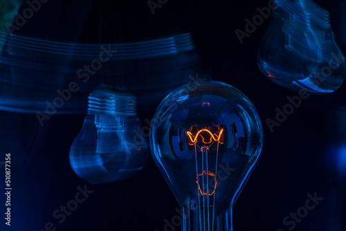 Glowing lamp, tungsten light bulb lit on black background,  close up shot, on wood table,  idea concept,  natural wax candle, Burning candle near a switched off light bulb in complete darkness.