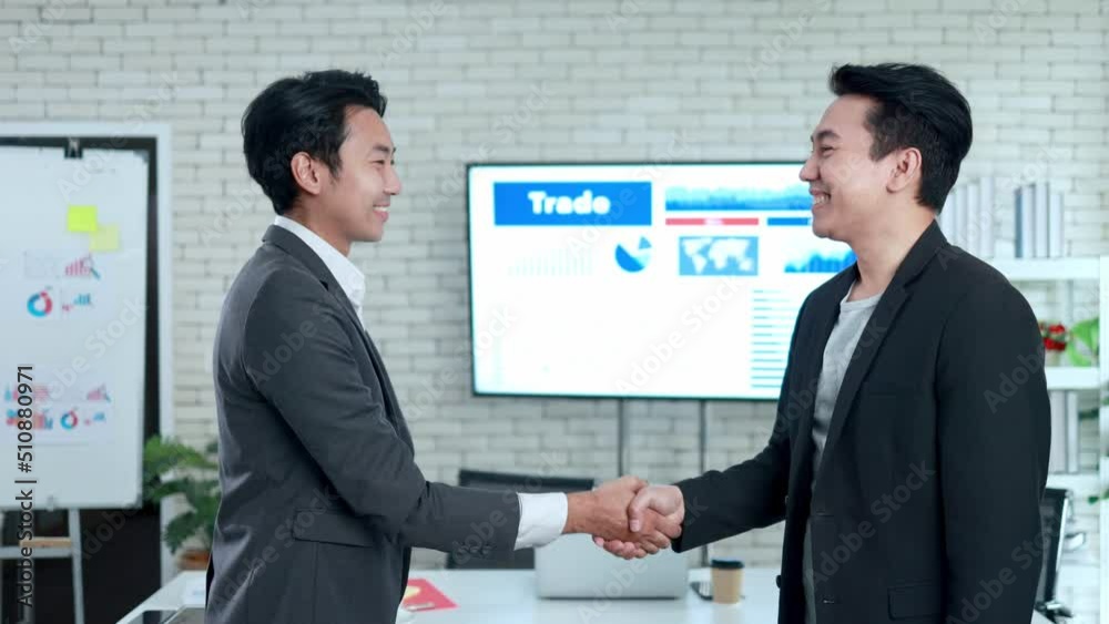 Asian business men in suit shake hands and agree to do business together in the office Asian business men in suit shake hands and agree to do business together in the office