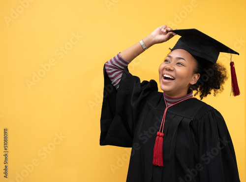 Pretty African american woman with black hair graduate bechalor degree.Education successful university college woman smiling  achievement Academic graduate.Isolated person yellow blackground design.