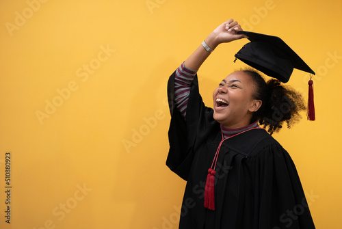 Pretty African american woman with black hair graduate bechalor degree.Education successful university college woman smiling  achievement Academic graduate.Isolated person yellow blackground design. photo