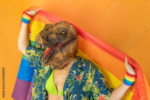 Portrait of happy man wearing dinosaur and hawaiian shirt holding pineapple fruit in hand.Funny celebration with copy space isolated on studio orange background.