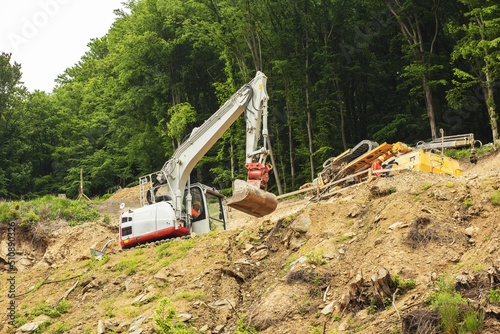 Excavator working on construction of higway on the steep slope of the hill. photo