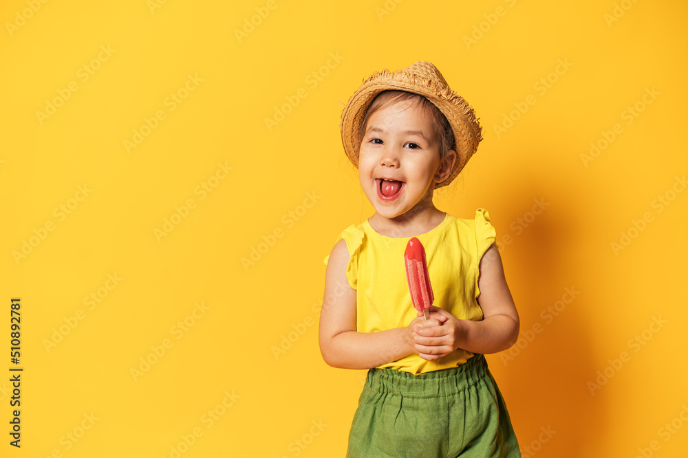 Asian girl holding ice cream on stick in front of yellow background.
