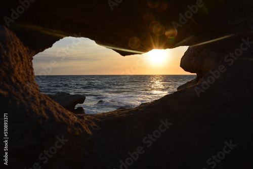 Sonnenuntergang überm Ozean, gerahmt durch Felsspalt.