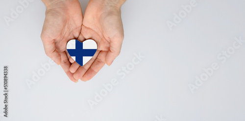 The national flag of Finland of arms in female hands. Flat lay, copy space.