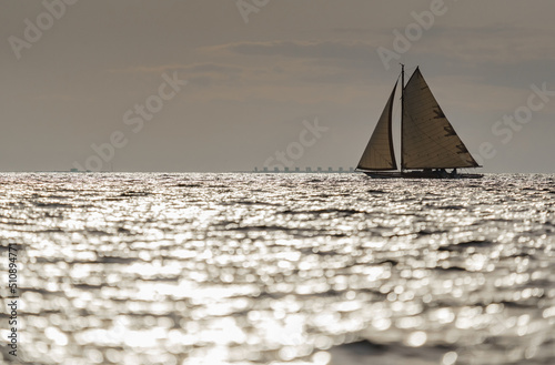 Classic sailing yacht in sea at sunset, the clear sky, sun reflection on water
