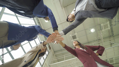 Group of Asian successful business people stacking hands together to cheer up team together in meeting, communicate, discuss, and working with colleagues in office. People lifestyle.Corporate teamwork