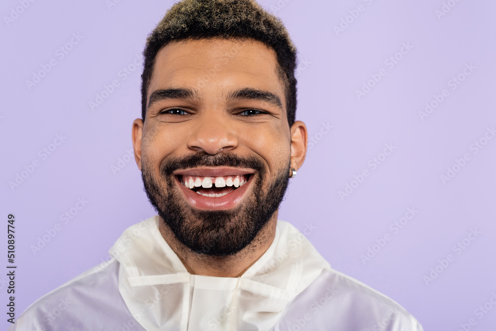 portrait of happy african american man smiling and looking at camera isolated on purple.