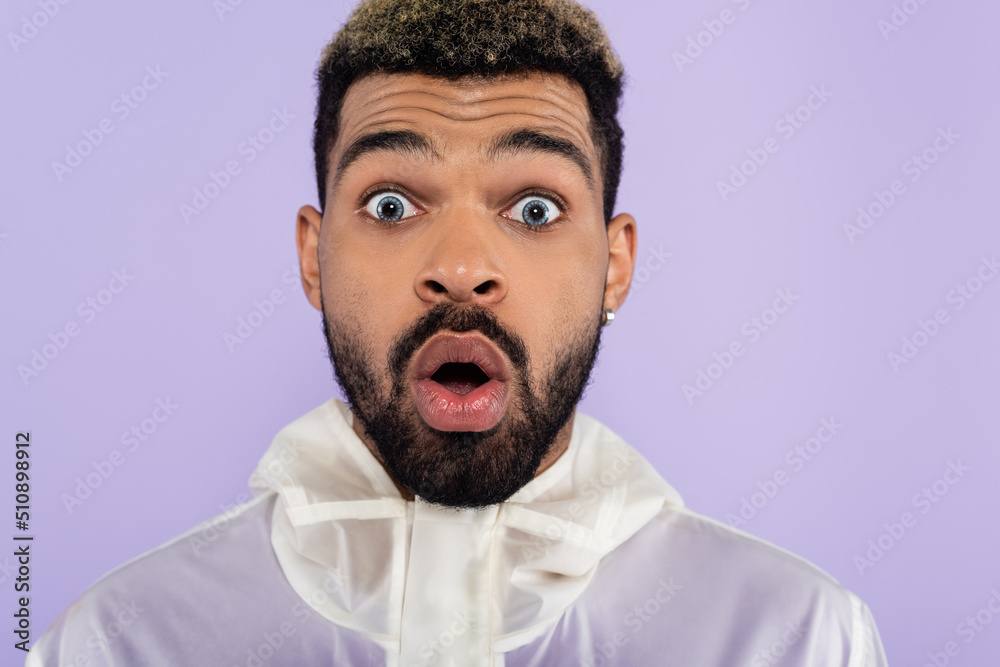 portrait of shocked african american man with blue eyes isolated on purple. portrait of shocked african american man with blue eyes isolated on purple.