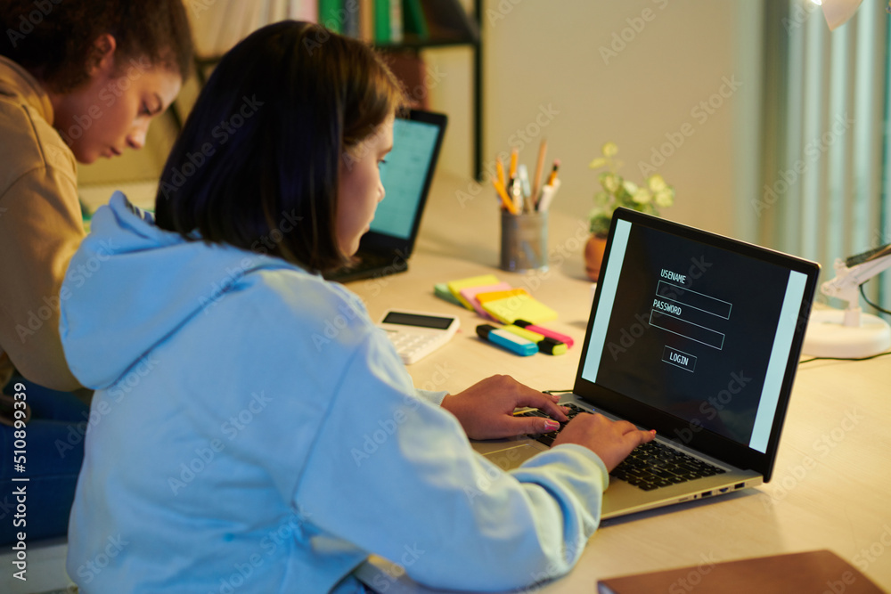 Fototapeta premium Schoolgirl entering e-mail and password to get access to online learning platform