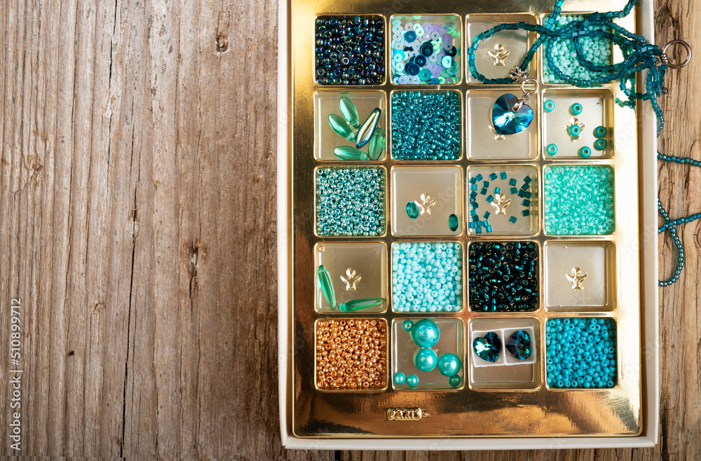 different azure beads and chrystals in box around old style wooden background. close up