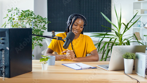 African American Streamer Leads a Podcast and Answers Questions in a Recording Studio, Smiling, Enjoying the Conversation. Podcasts and Audio Blogging Concept.