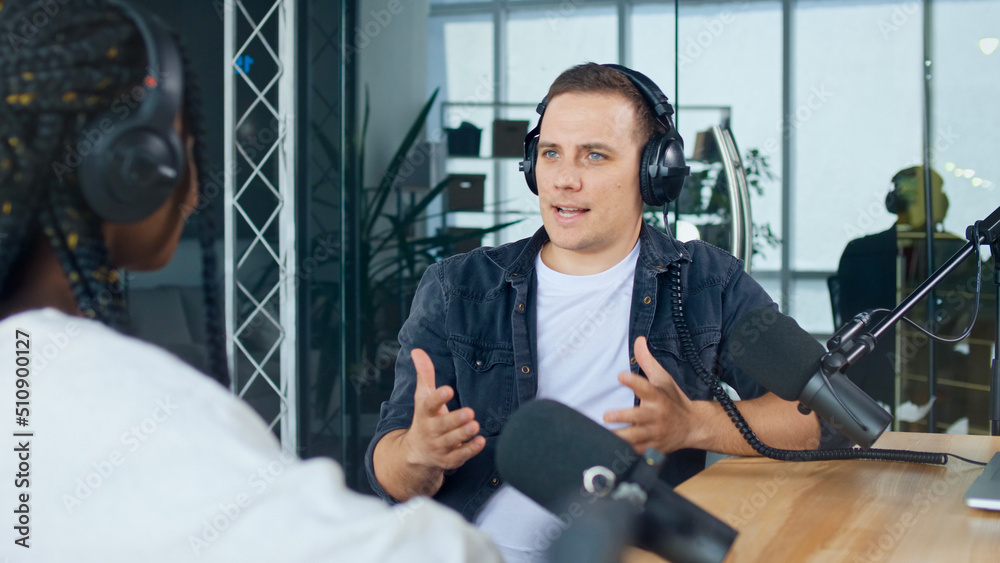 A Male Presenter Communicates with a Guest, an African American, During a Radio Broadcast at a Table in a Recording Studio, Broadcasts a Live Radio Interview With Spbd. A Male Presenter Communicates with a Guest, an African American, During a Radio Broadcast at a Table in a Recording Studio, Broadcasts a Live Radio Interview With Spbd.