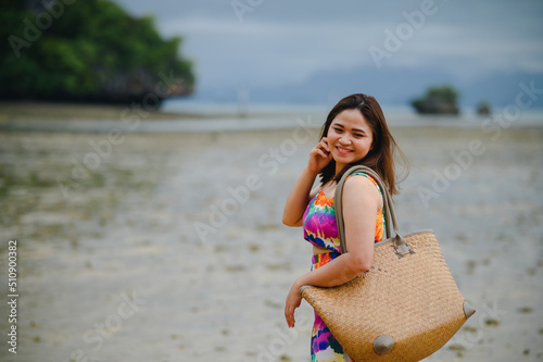 Baeautiful asian woman carrying a bag happy smile by the sea photo