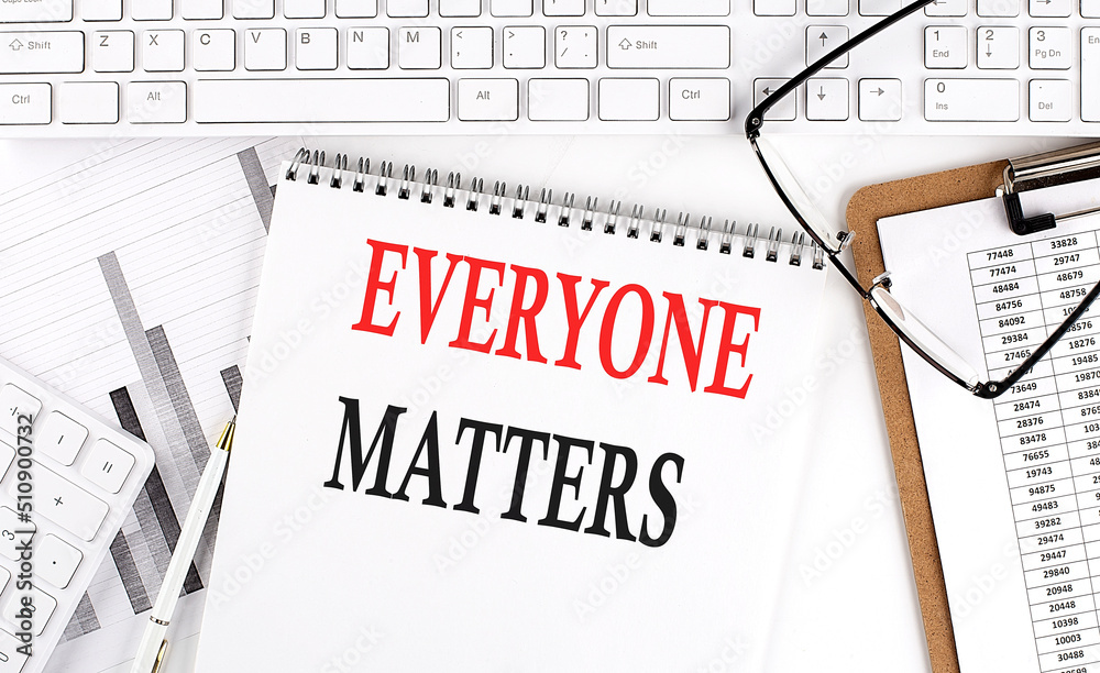 Text EVERYONE MATTERS on Office desk table with keyboard, notepad and analysis chart on white background. Text EVERYONE MATTERS on Office desk table with keyboard, notepad and analysis chart on white background.
