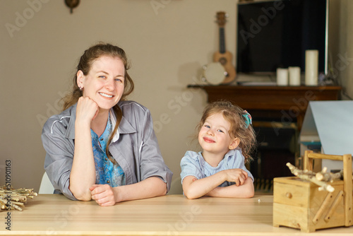 Have fun together. Smile and laugh at home. Happy family at table. Motherhood is joy. Children laughter. Kid play. woman babysitter is good for sister. White dresses on caucasian women. tickles girl