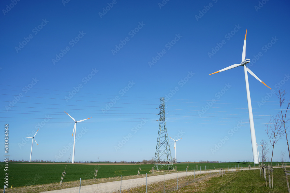 Windmills and power lines in one line, sky, field