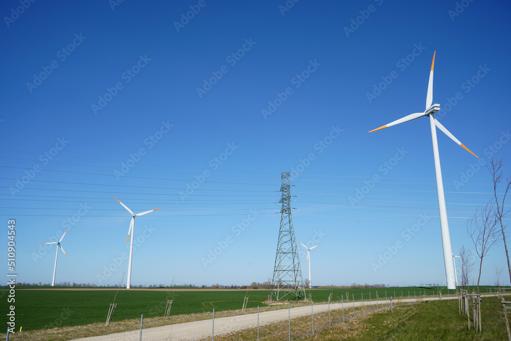 Windmills and power lines in one line, sky, field Windmills and power lines in one line, sky, field