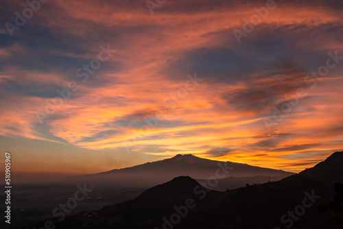 Panoramic view on silhouette of hills during twilight. Watching beautiful sunset behind volcano Mount Etna near Castelmola  Taormina  Sicily  Italy  Europe  EU. Clouds with vibrant red orange colors