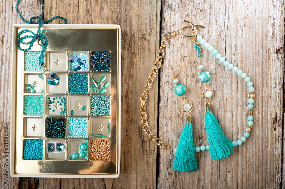 different azure beads and chrystals in box handmade jewelry around old style wooden background. close up