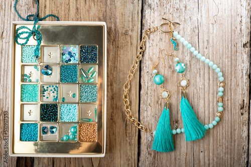 Obraz na płótnie different azure beads and chrystals in box handmade jewelry around old style wooden background. close up w salonie