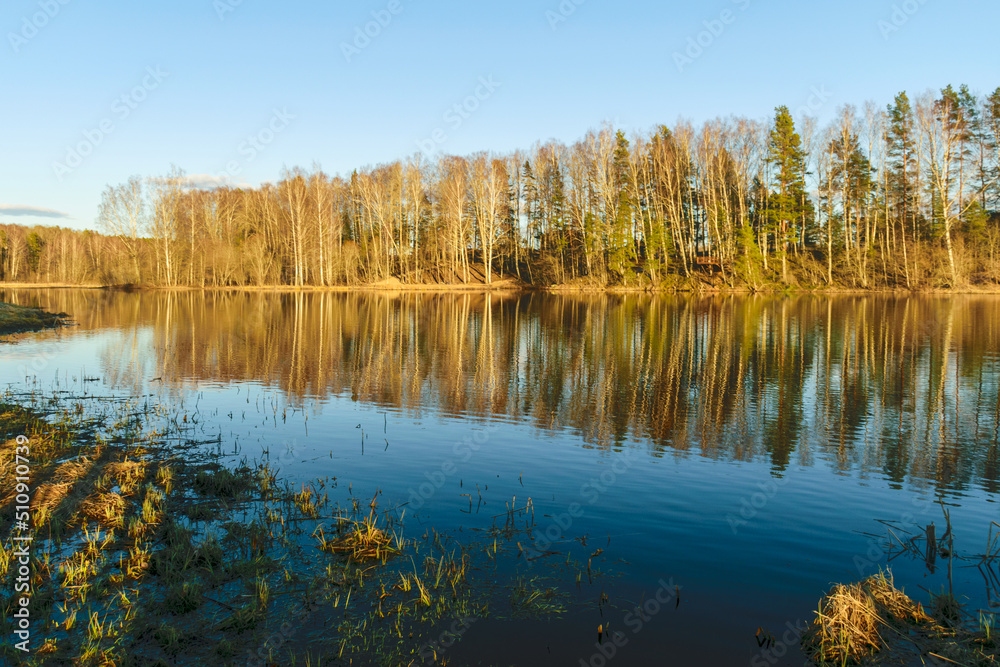 spring landscape with reflections of lakes, clouds and trees on a calm water surface spring landscape with reflections of lakes, clouds and trees on a calm water surface