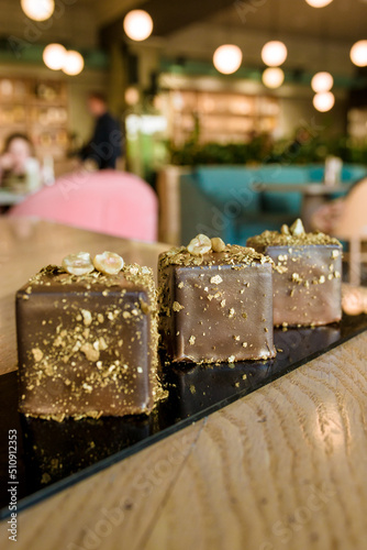 sweet chocolate cakes with gold topping and nuts on the table in a restaurant