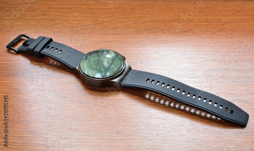 The smartwatch lies on a surface with a wooden texture. Close-up