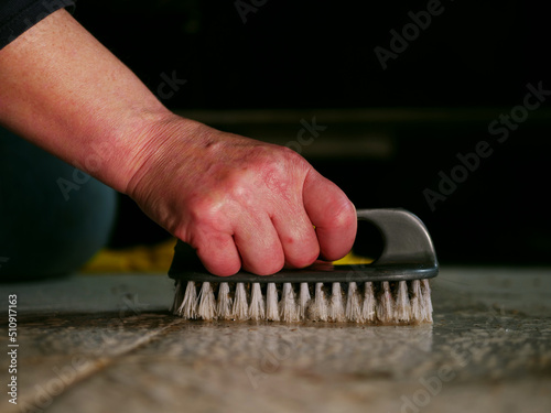 Woman scrubbing dirty floor with brush medium shot