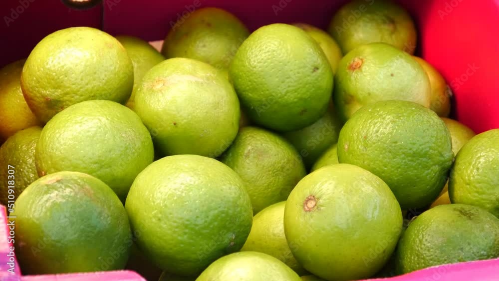 Close-up of many beautiful ripe limes in a trading box and a male hand takes one Close-up of many beautiful ripe limes in a trading box and a male hand takes one