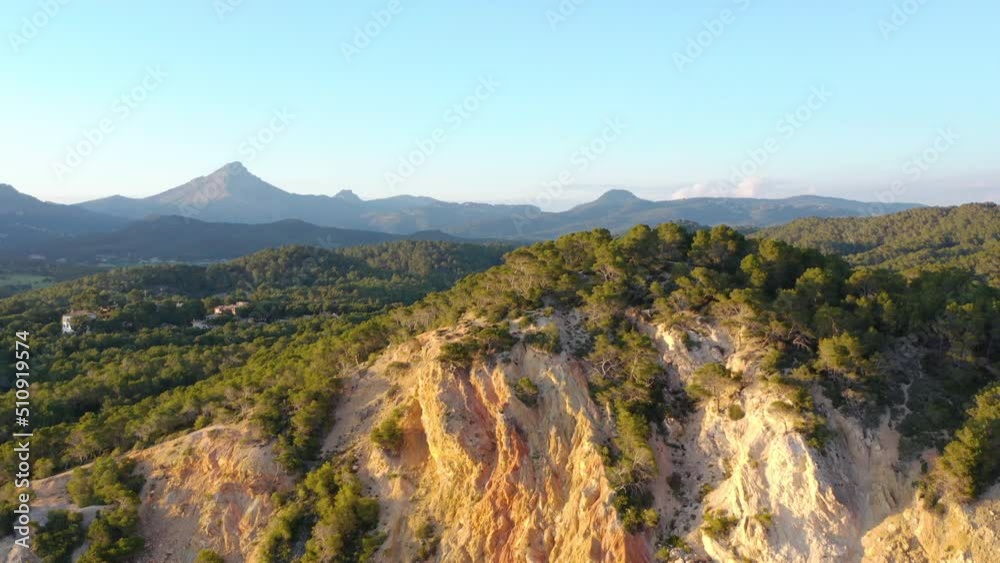 Aerial fly by shot of coastal cliffs in Peguera from sea side. Mountains in background. Mallorca, Balearic Islands, Spain