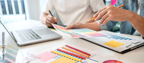 Two creative graphic designer team working on color selection and drawing on graphic tablet, Color swatch samples chart for selection coloring in inspiration to creativity at workplace