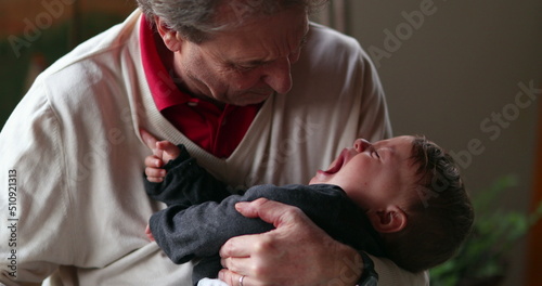 Upset baby with grand-father. Grand-parent consoling crying grand-child