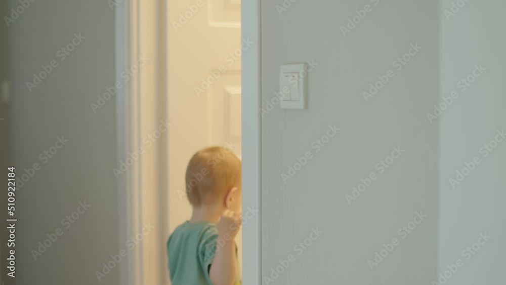 little baby toddler child switching on light in room, kid turn on switch on wall. caucasian child in green shirt get hands on reaching light toggle and turns it, entering coming into room