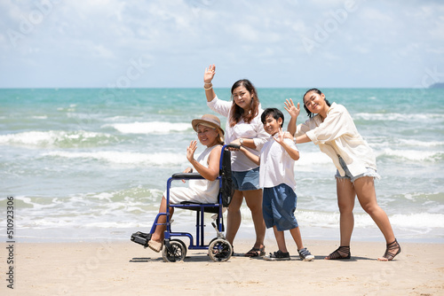 disabled woman in a wheelchair with family and goodbye pose on the beach
