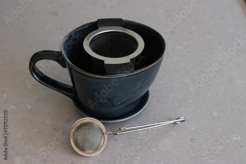 Tea filters  tea infuser next to an empty tea cup made of ceramic on a white table