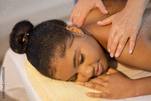 relaxation of beautiful african young woman at specialist on back massage