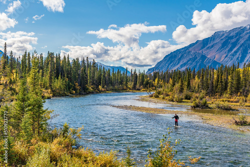 Fotografie, Tablou One person fishing in northern Canada during fall with scenic mountains in the background